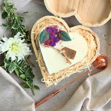 Große herzförmige Kerze mit Fliederblüten in einer Holzherz-Geschenkbox